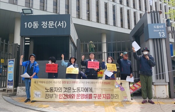 전국활동지원사노동조합이 14일 정부세종청사 보건복지부 앞에서 기자회견을 갖고, 활동지원 바우처수가를 인건비와 운영비로 구분지급할 것을 거듭 요구했다.(노동자의 것은 노동자에게, 정부가 인건비와 운영비를 구분 지급하다 현수막을 들고있음)ⓒ전국활동지원사노동조합  출처 : 에이블뉴스(http://www.ablenews.co.kr)