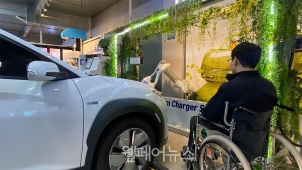 서울시는 지난 13일 전국 최초로 로봇을 활용해 비대면, 비접촉으로 전기차를 충전하는 ‘무인 로봇충전시스템’ 전기차 충전 실증 사업을 추진한다고 밝혔다. / 무인 로봇충전시스템을 사용해 전기차를 충전하고 있는 휠체어 이용자. ⓒ서울시  출처 : 웰페어뉴스(http://www.welfarenews.net)